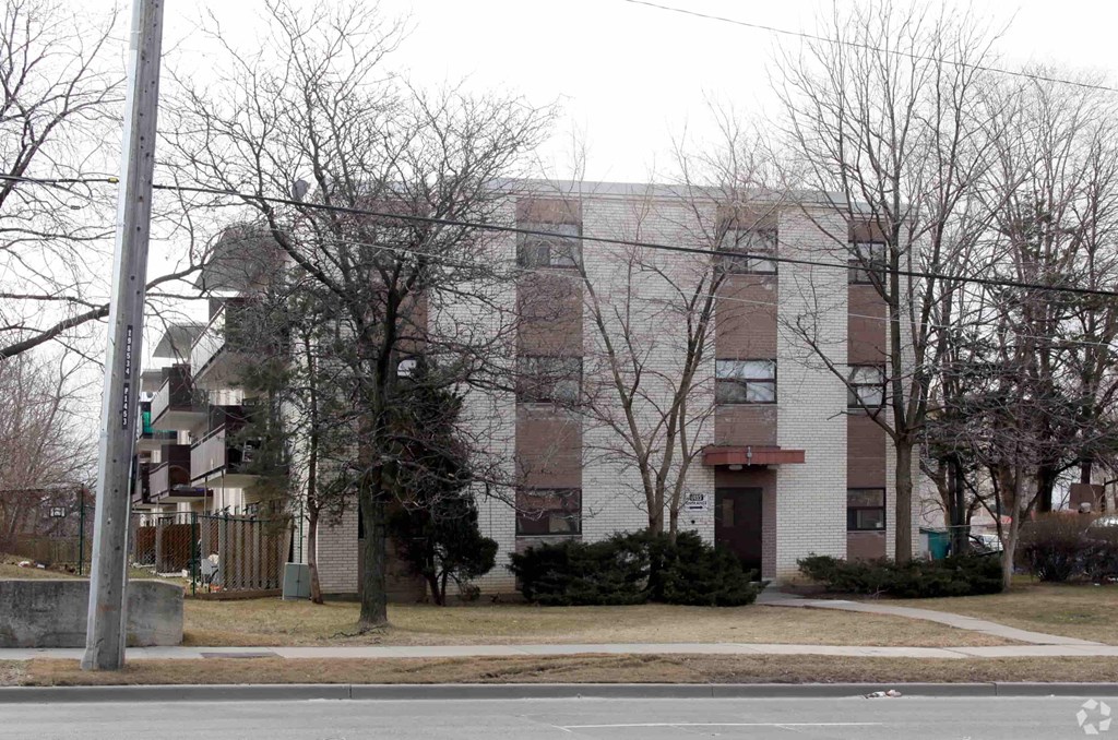 A building with a brown and white facade is surrounded by bare trees.