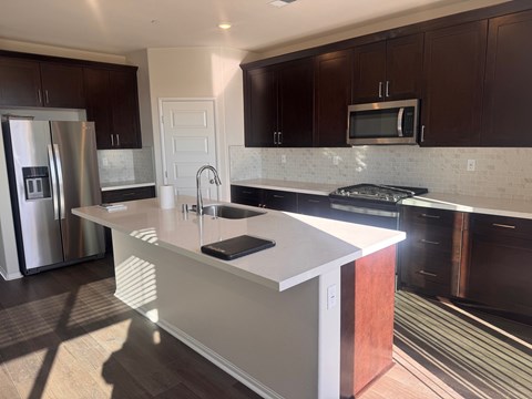 A kitchen with a white island and dark brown cabinets.