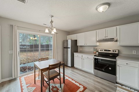 A kitchen with white cabinets and a wooden table.