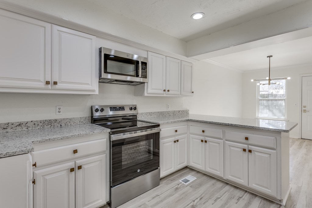 A kitchen with white cabinets and a granite countertop.