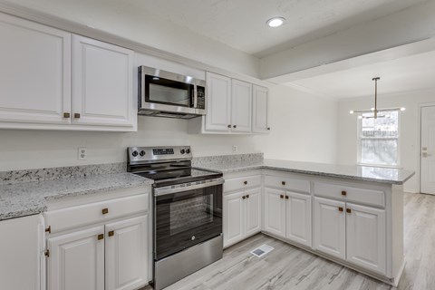 A kitchen with white cabinets and a granite countertop.