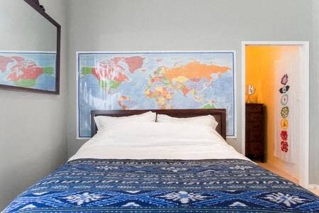 A bedroom with a world map on the wall and a bed with a blue comforter.