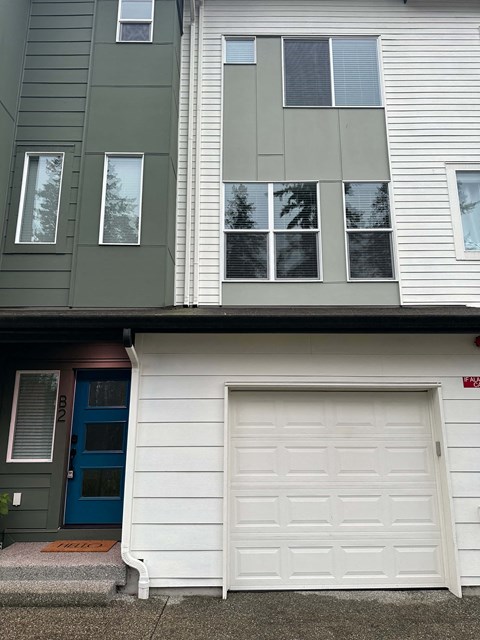 A white garage door in front of a white house.