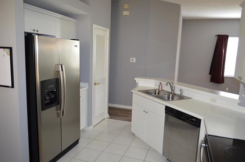 A kitchen with a refrigerator, sink, and oven.