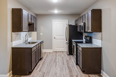 A kitchen with dark brown cabinets and a black refrigerator. A kitchen with dark brown cabinets and a black refrigerator at Mode at Melbourne, LLC Apartments, Florida, 32901