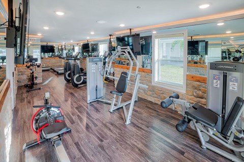 A gym with a variety of equipment including a stationary bike, a leg press machine, and a cable machine. A gym with a variety of equipment including a stationary bike, a leg press machine, and a cable machine at Mode at Melbourne, LLC Apartments, Melbourne, 32901