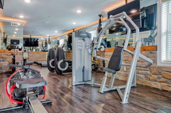 A gym with a variety of equipment including a leg press machine and a cable machine at Mode at Melbourne, LLC Apartments, Melbourne, FL