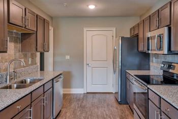 A kitchen with brown cabinets and a black refrigerator at Mode at Melbourne, LLC Apartments, Melbourne
