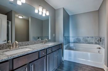 A bathroom with a large mirror, two sinks, and a bathtub at Mode at Melbourne, LLC Apartments, Melbourne, 32901