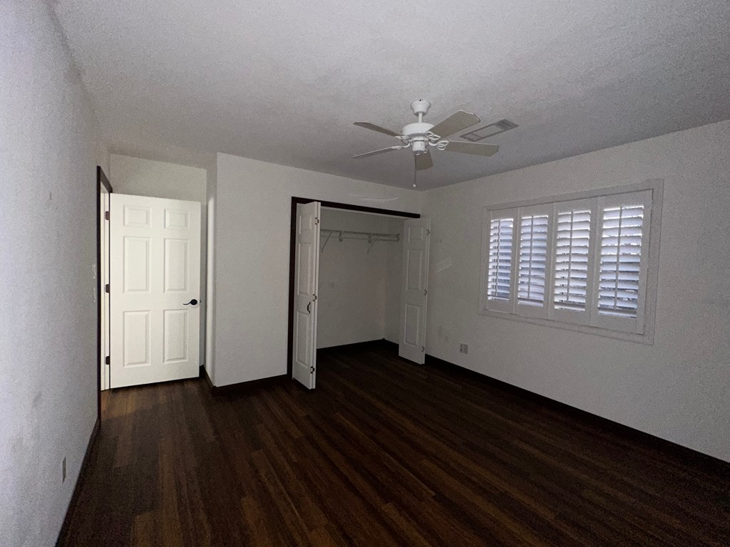 A room with a ceiling fan and wooden floors.