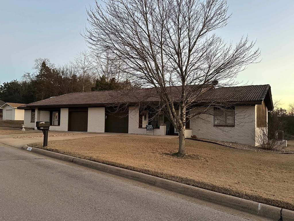 A house with a brown roof and a tree in front of it.