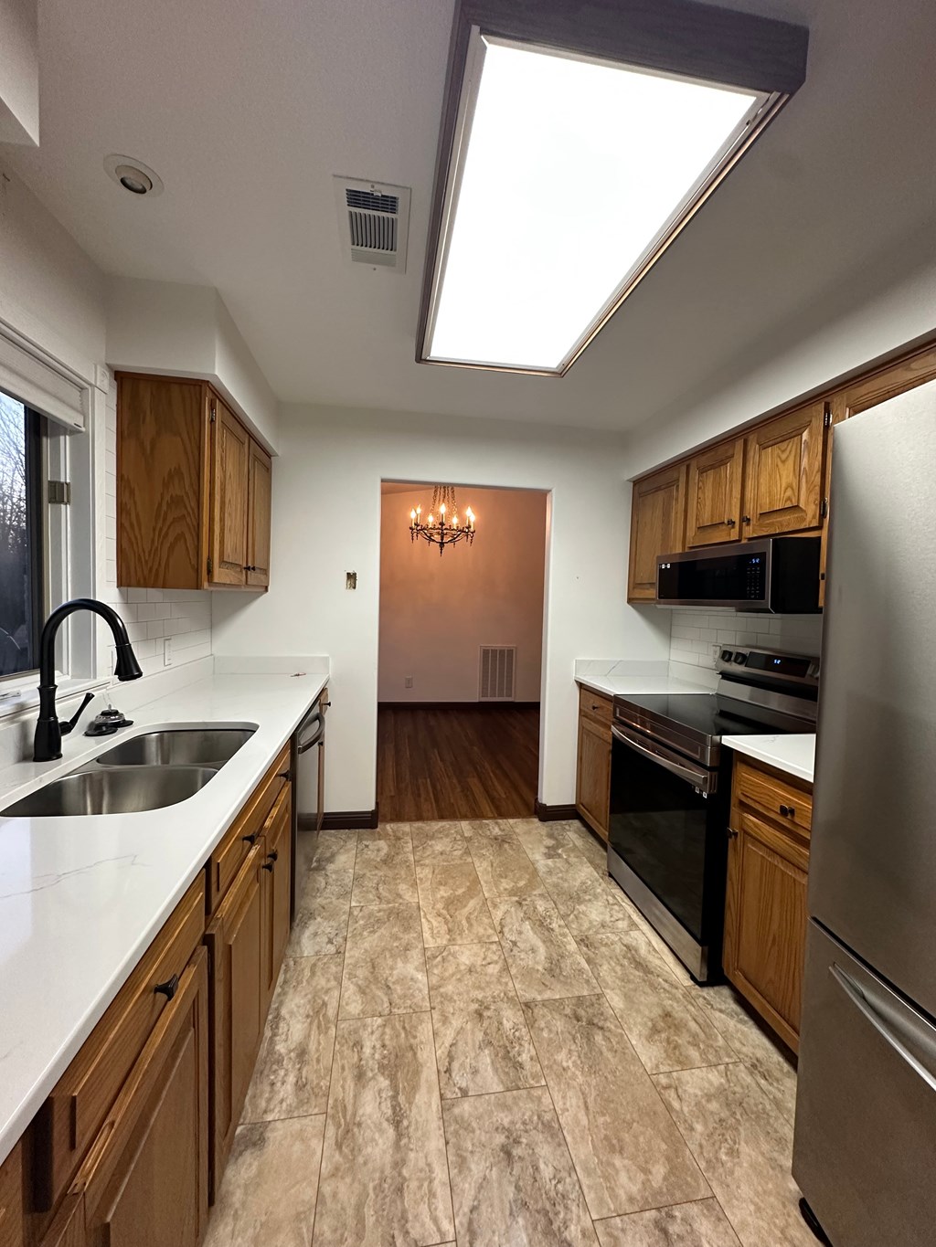 A kitchen with a refrigerator, sink, and microwave.
