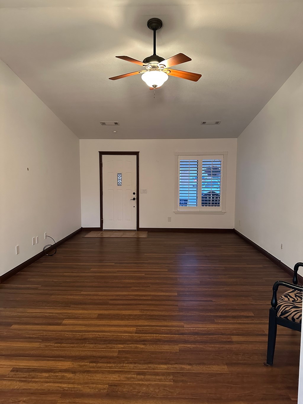 A room with a ceiling fan and a chair.