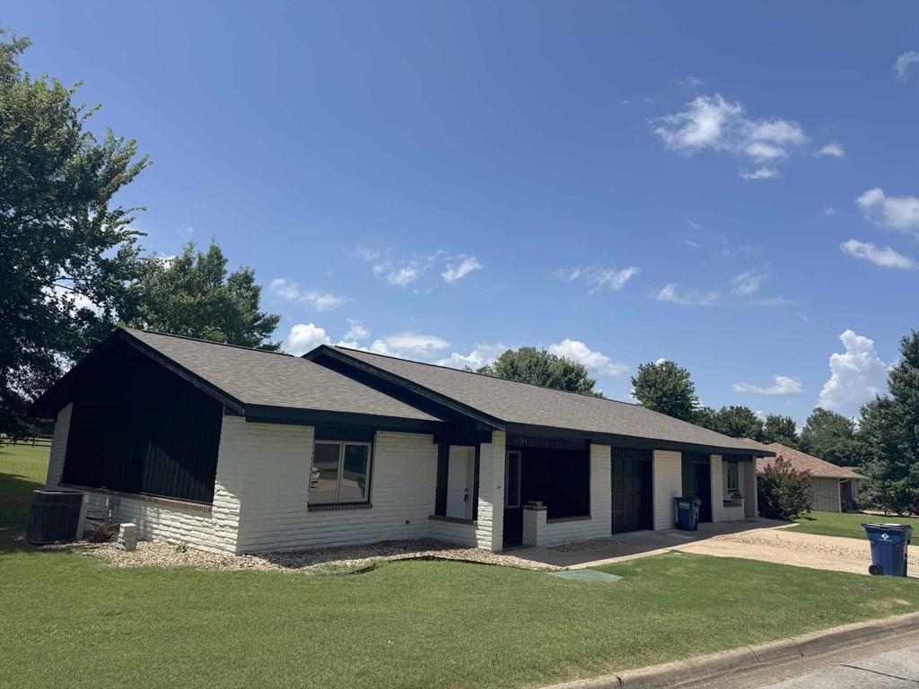 A white house with a black roof and a grey garage door.