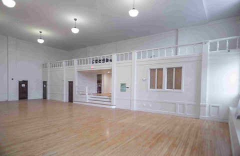 A large empty room with wooden floors and white walls.