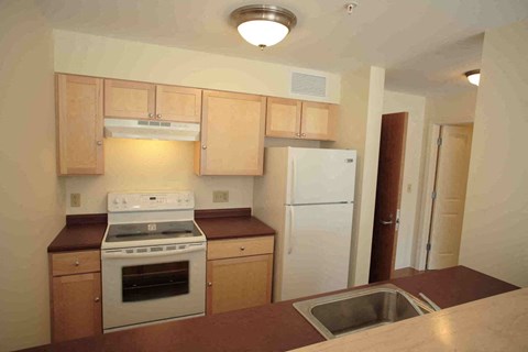 A kitchen with a white refrigerator, white stove, and wooden cabinets.