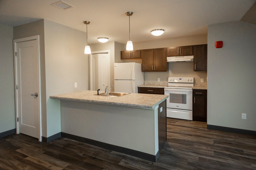 A kitchen with a white island and wooden floors.