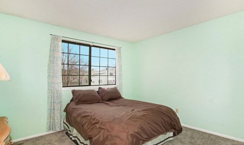A bedroom with a bed and a window.