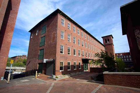 A red brick building with a green door and windows.
