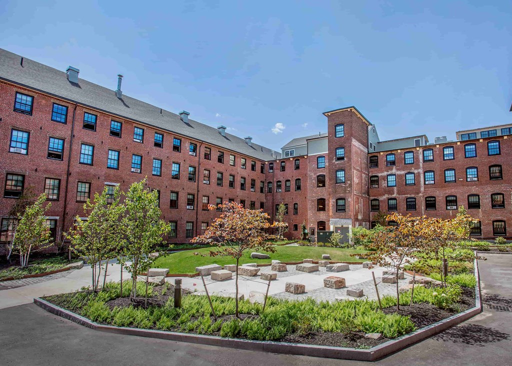 A courtyard with a garden in front of a red brick building.