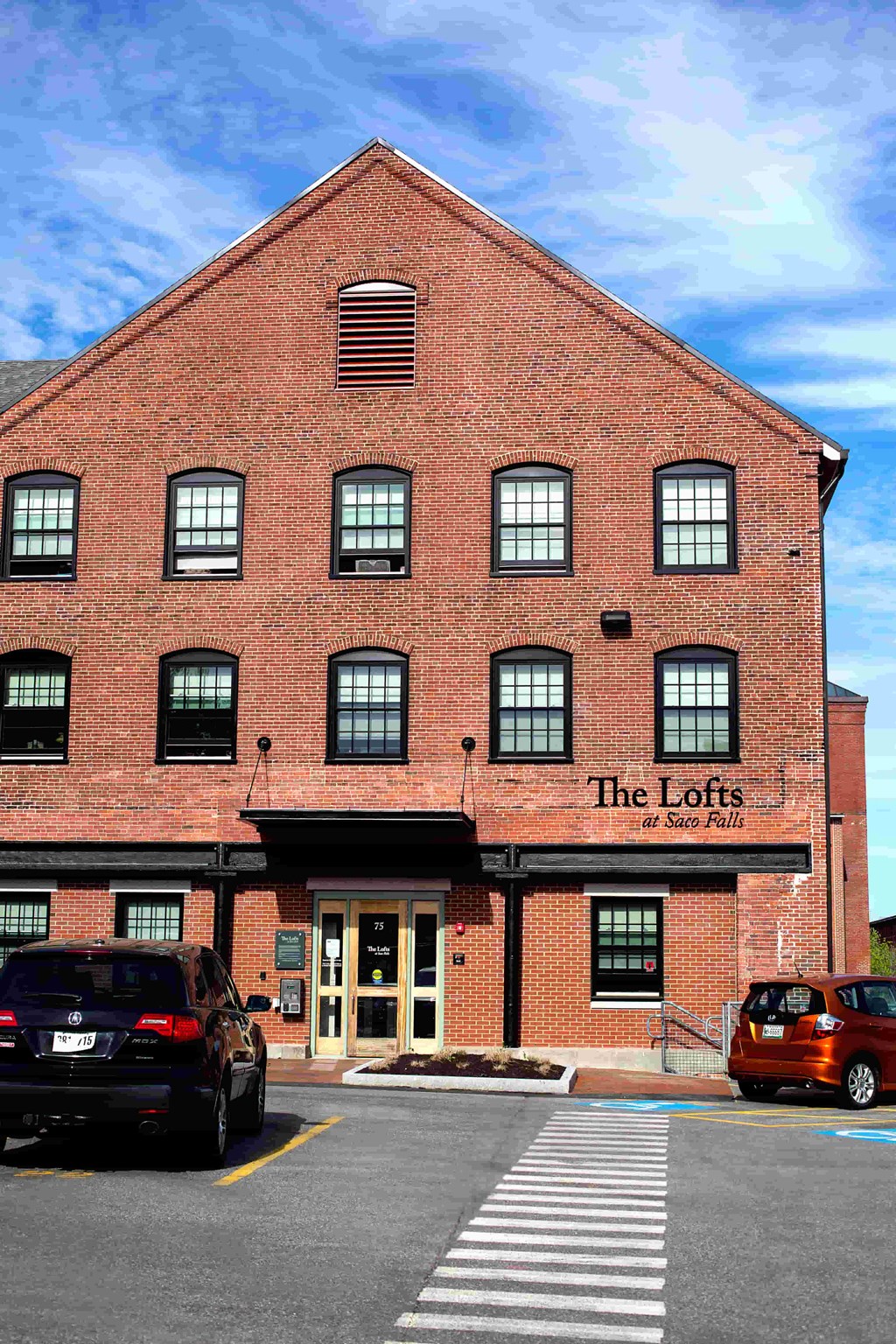 The Lofts at Stone Pits is a red brick building with a parking lot in front.