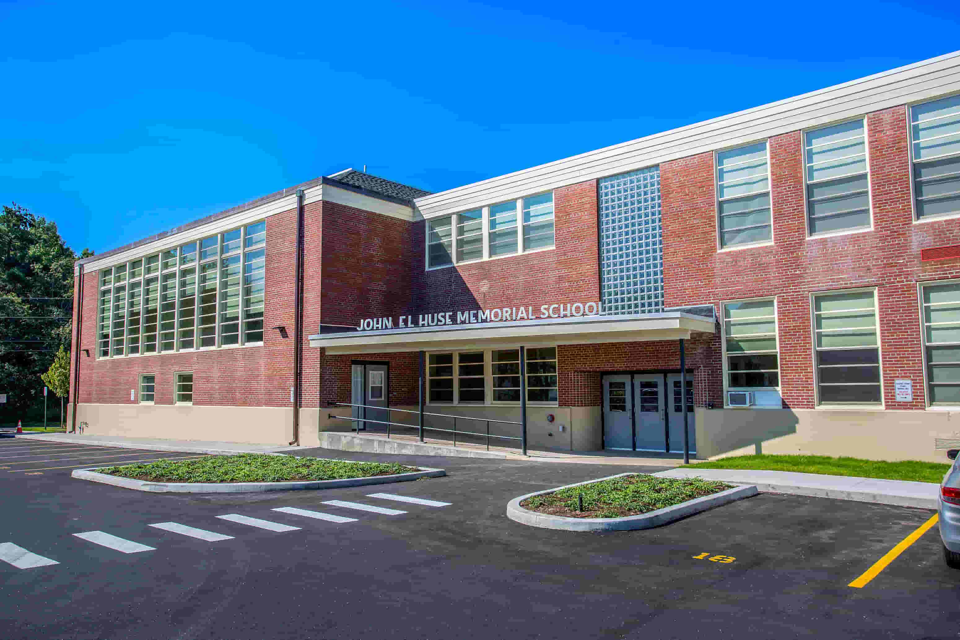 John F. Kennedy Memorial School is a red brick building with a parking lot in front.