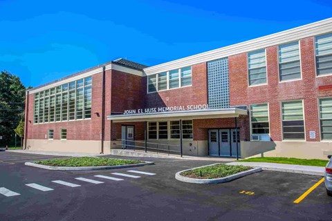John F. Kennedy Memorial School is a red brick building with a parking lot in front.