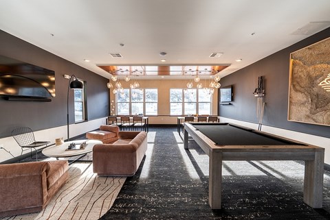 A modern living room with a pool table and a large painting on the wall.