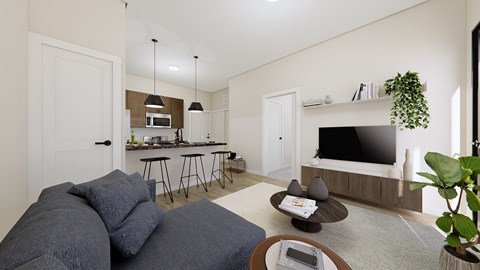 A living room with a grey couch and a television on the wall.
