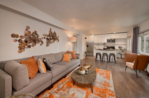 A modern living room with a grey couch and orange pillows.
