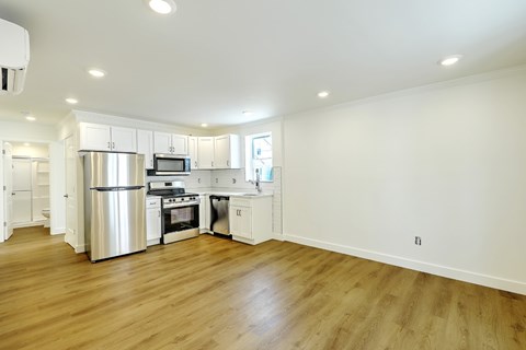A kitchen with white cabinets and a wooden floor.