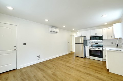 A kitchen with white cabinets and a wooden floor.