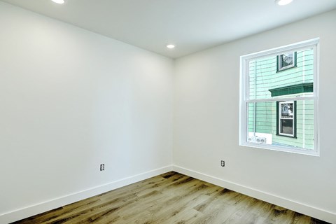 A room with a window showing a house and trees outside.
