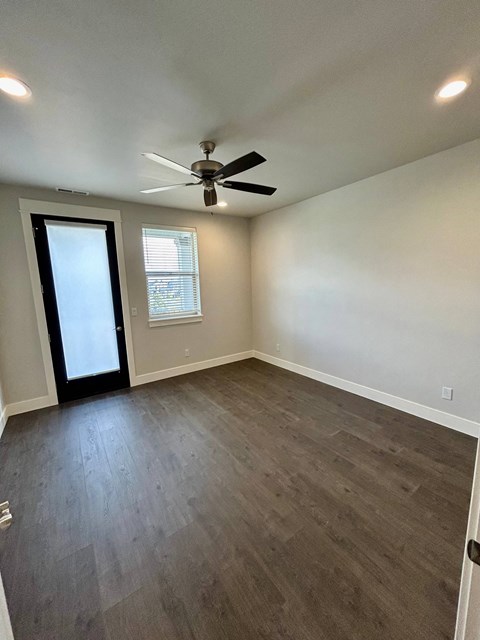 A room with a ceiling fan and a door leading to a balcony.