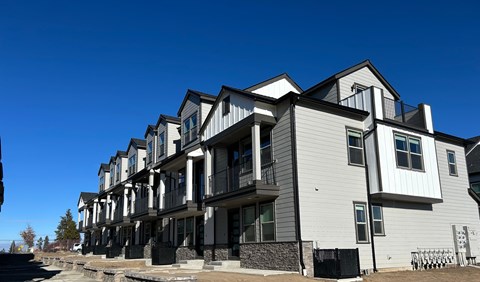 A row of modern townhouses with balconies and black railings.