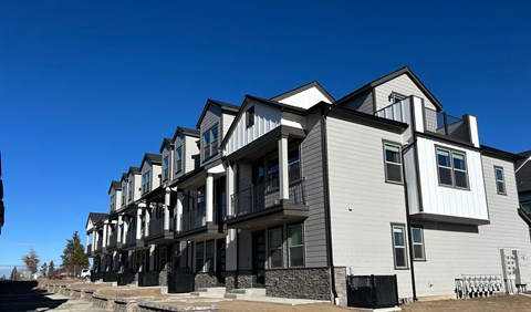 A row of modern townhouses with balconies and black railings.