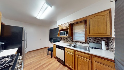 A kitchen with wooden cabinets and a black fridge.