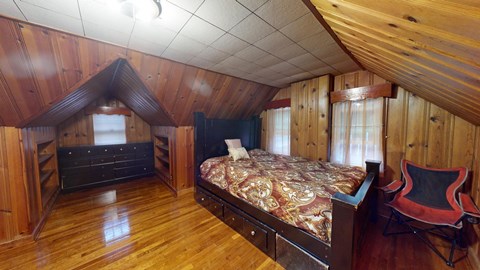 A bedroom with a bed, chair, and wooden walls.
