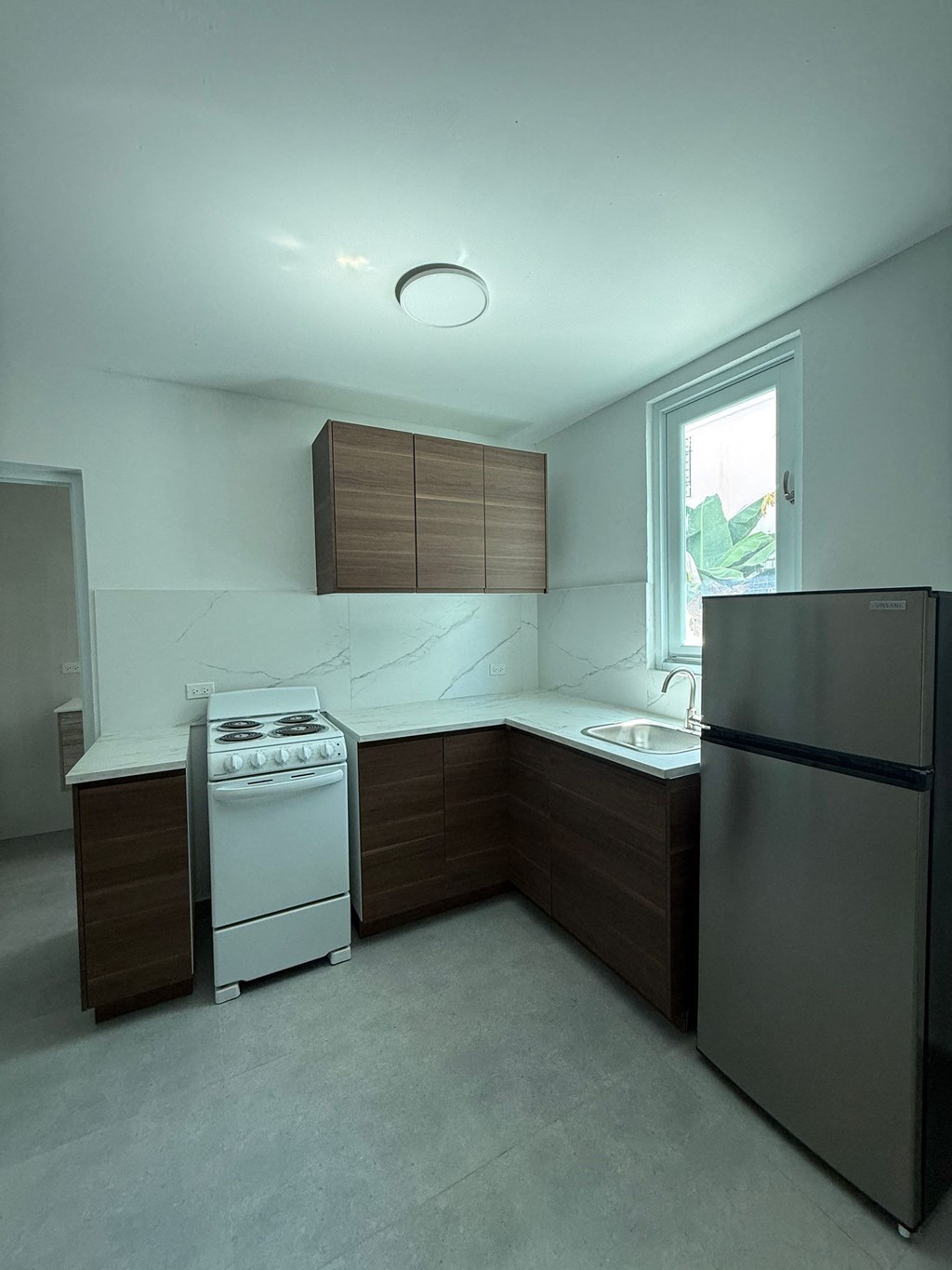 A kitchen with a white stove and a black refrigerator.
