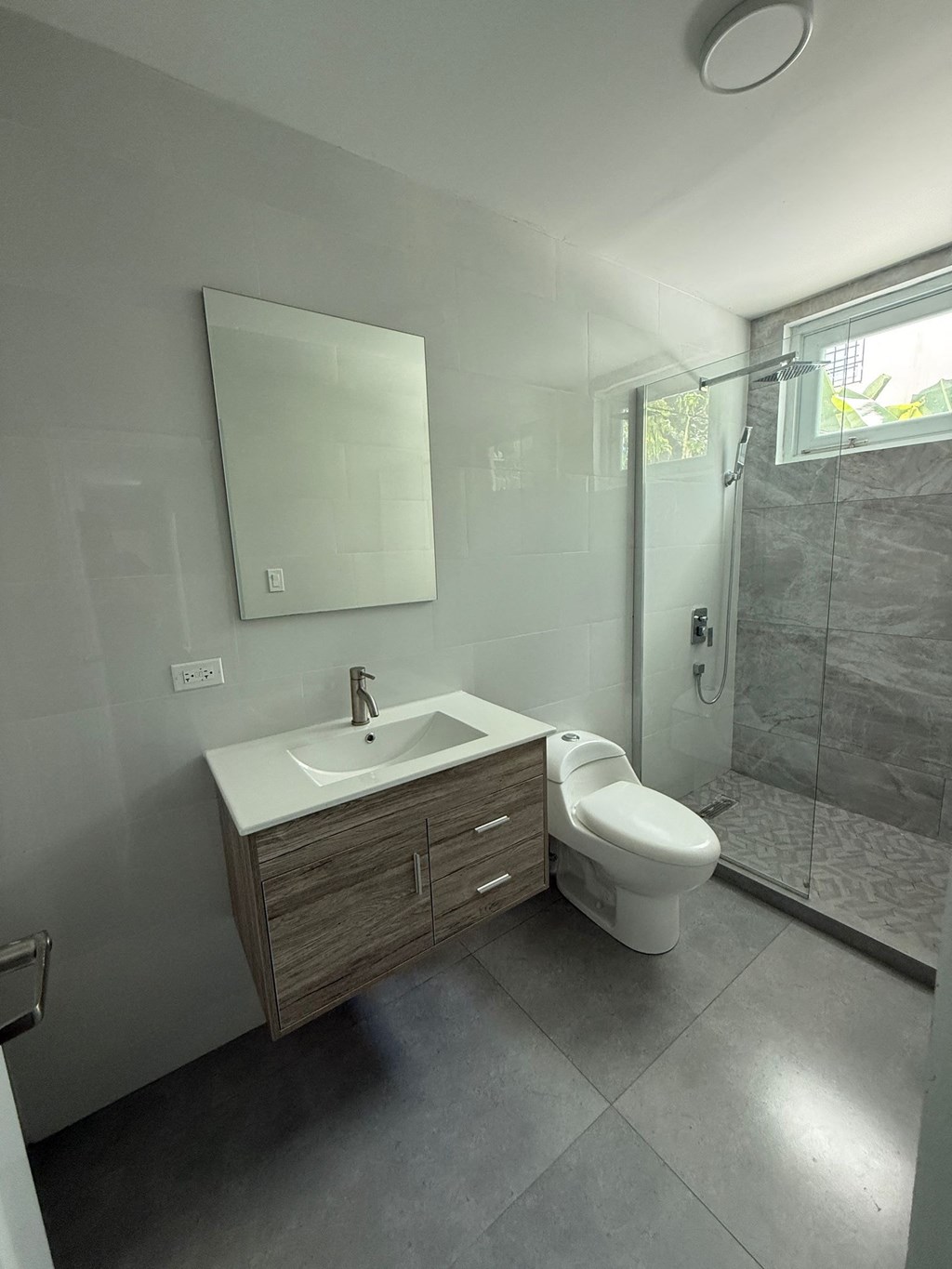 A modern bathroom with a toilet, sink, and mirror.