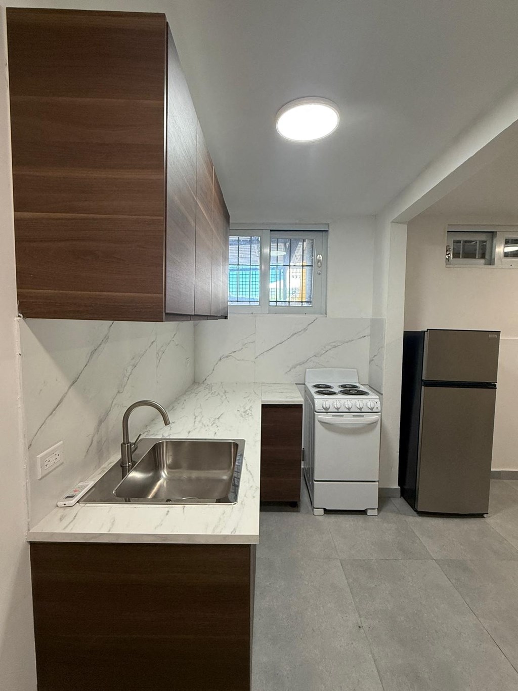 A kitchen with a sink, a stove, and a refrigerator.