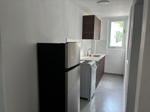A black refrigerator in a kitchen with a white counter.
