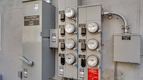 A series of meters and switches are attached to a grey wall.