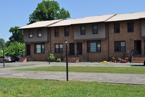 A brick building with a metal roof and a car parked in front.