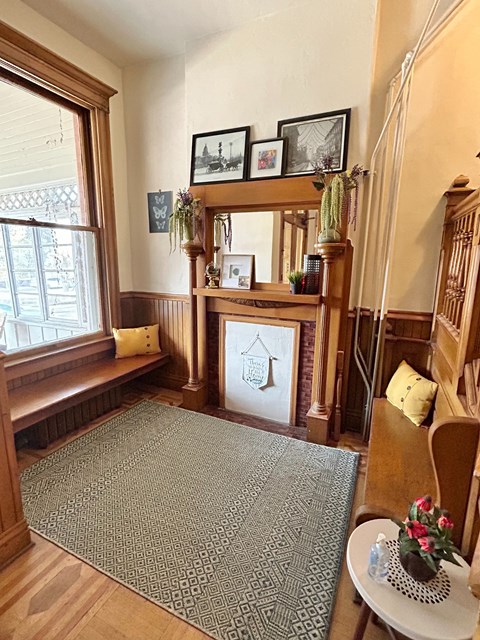 A living room with a fireplace and a grey rug.