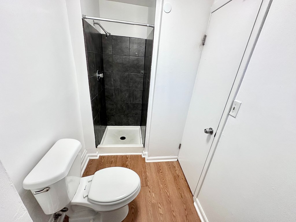 A white toilet with a white tank and a white door in a bathroom.