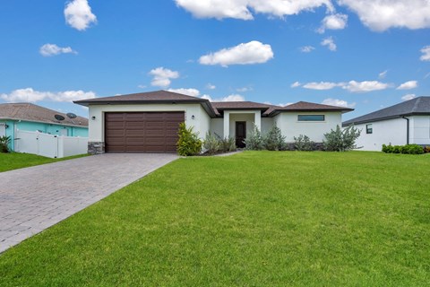 A house with a brown garage door is surrounded by a well-kept lawn.