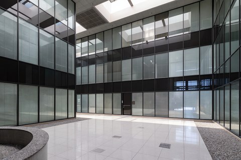 A modern atrium with glass walls and a white floor.
