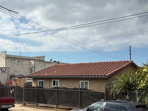 A house with a red tile roof is surrounded by a black fence.
