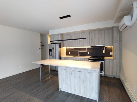 A kitchen with a white countertop and wooden cabinets.